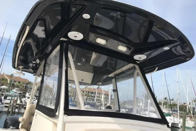 Slide: The Image of 2016 Cobia 344 Center Console boat with sleek black hardtop in marina setting. - 17