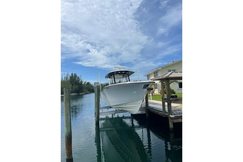 Slide: The Image of 2016 Cobia 344 Center Console boat docked by a waterfront home under a clear sky. - 21