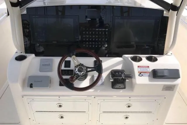 Slide: The Image of 2016 Cobia 344 Center Console helm with steering wheel, controls, and navigation displays. - 16