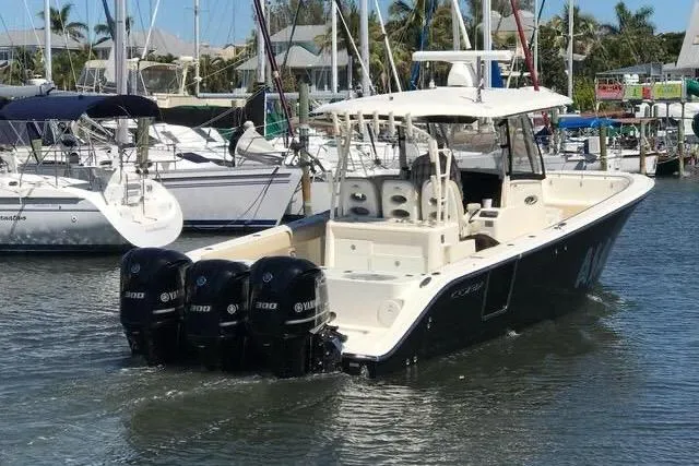 Slide: The Image of 2016 Cobia 344 Center Console boat with triple Yamaha engines in a marina setting. - 1