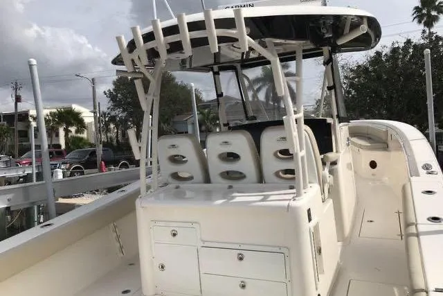 Slide: The Image of 2016 Cobia 344 Center Console boat with seating and storage, docked under cloudy skies. - 6