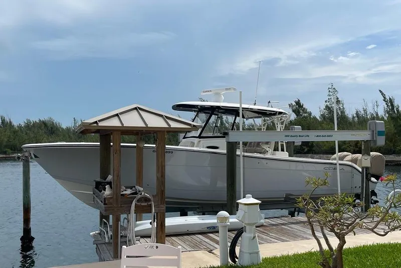 Slide: The Image of 2016 Cobia 344 Center Console boat docked on a lift by the water. - 2