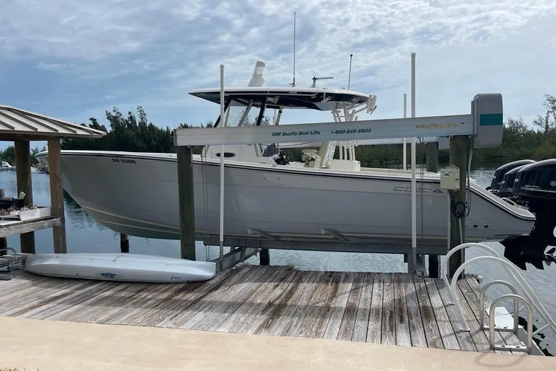 The Image of 2016 Cobia 344 Center Console boat on lift at dockside, under cloudy sky. - 0