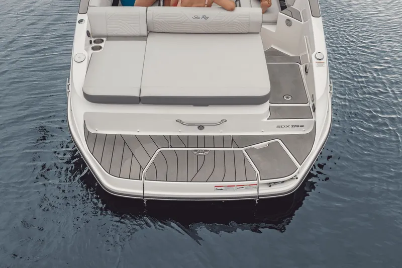 Slide: The Image of The image shows the stern of a 2025 Sea Ray SDX 270 Surf boat on calm water. - 31