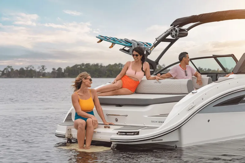 Slide: The Image of Three people relax on a Sea Ray SDX 270 Surf boat on a calm lake. - 27