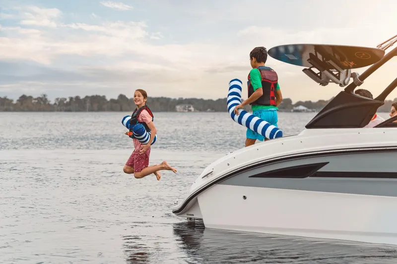 Slide: The Image of Two people jumping off a Sea Ray SDX 270 Surf boat into the water. - 40