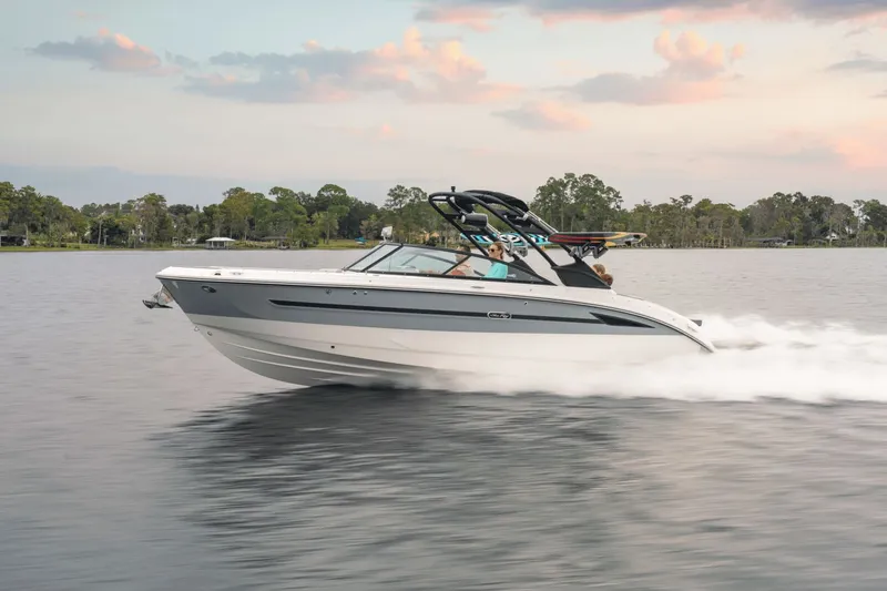 Slide: The Image of A 2025 Sea Ray SDX 270 Surf speeds across calm water at sunset. - 0