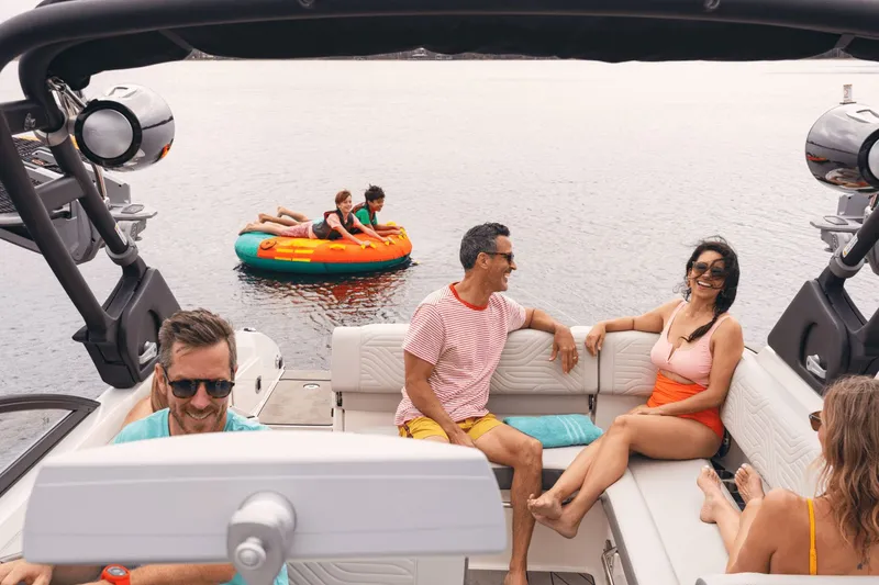 Slide: The Image of A group of people relax on a Sea Ray SDX 270 Surf boat, while children play on an inflatable water toy. - 14