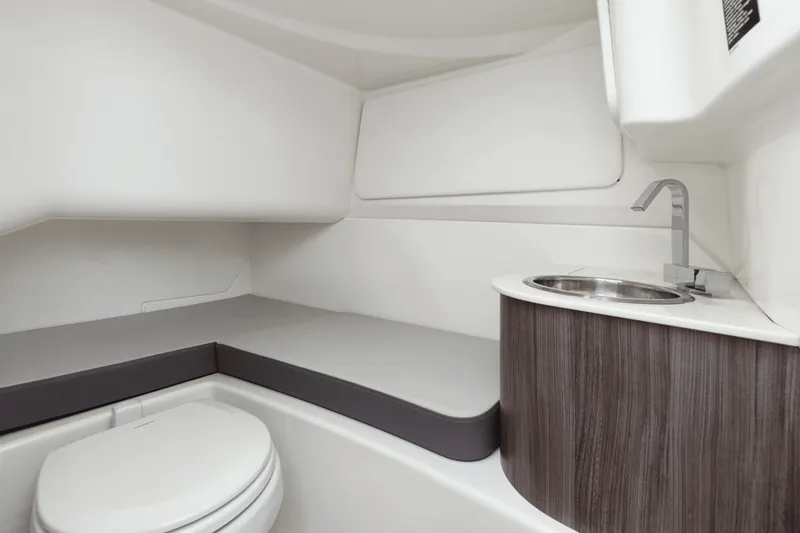 Slide: The Image of The cabin of the 2025 Sea Ray SDX 270 Surf features a compact toilet, sink, and cushioned bench. - 36