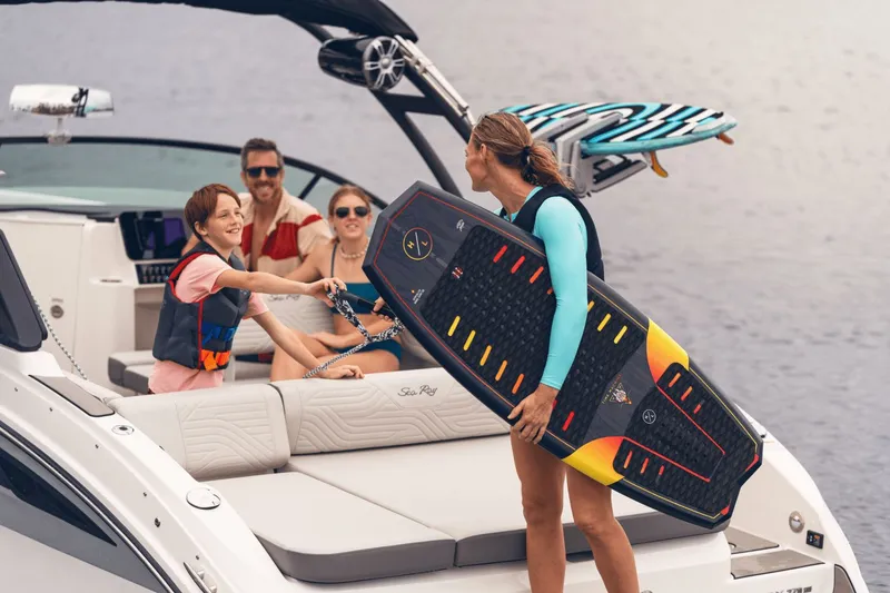 Slide: The Image of A family enjoys time on a Sea Ray SDX 270 Surf boat. A child hands an adult a surfboard. - 29