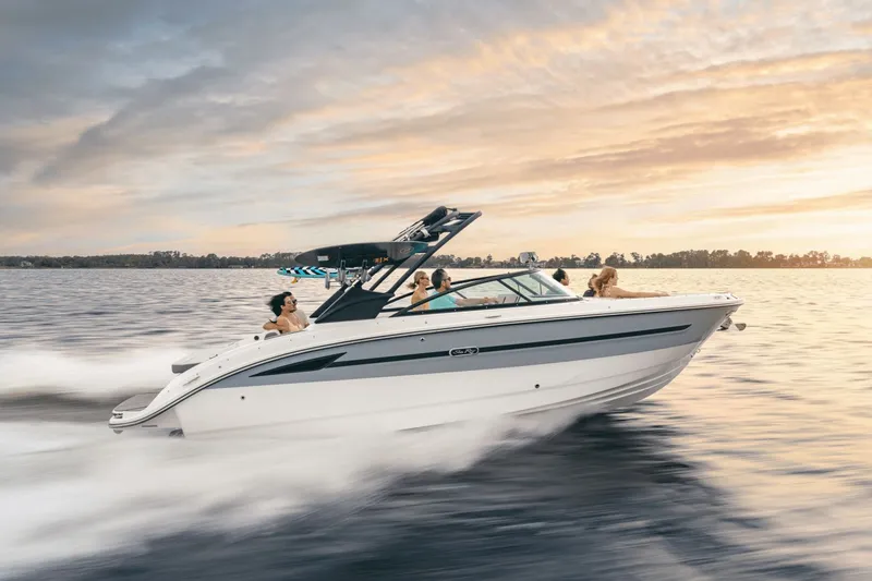 Slide: The Image of A 2025 Sea Ray SDX 270 Surf speeds across the water at sunset. - 2