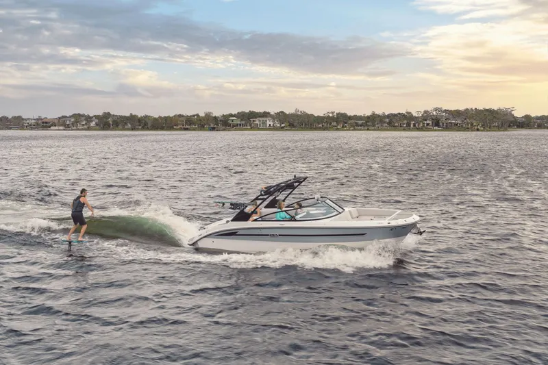 Slide: The Image of A 2025 Sea Ray SDX 270 Surf towing a wakeboarder across calm waters. - 21