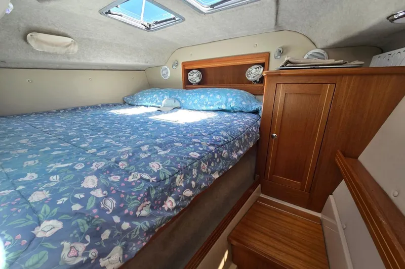 Slide: The Image of Cozy cabin interior of 2014 Aspen C100 with floral bedding and wooden cabinetry. - 9