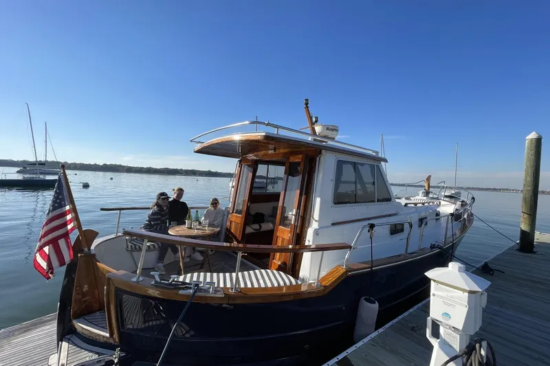 Slide: The Image of 2002 Menorquin 110 yacht docked, with people enjoying a sunny day on deck. - 7