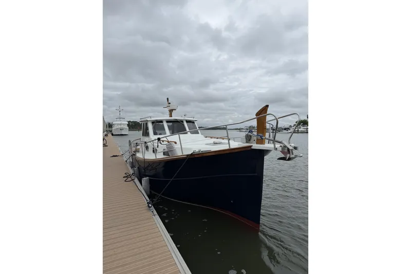 Slide: The Image of 2002 Menorquin 110 boat docked on a cloudy day, showcasing classic design and craftsmanship. - 2