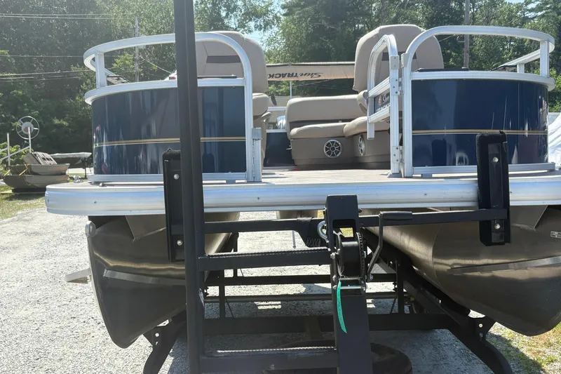 Slide: The Image of 2024 Sun Tracker Bass Buggy 16 DLX pontoon boat on trailer, parked outdoors. - 4