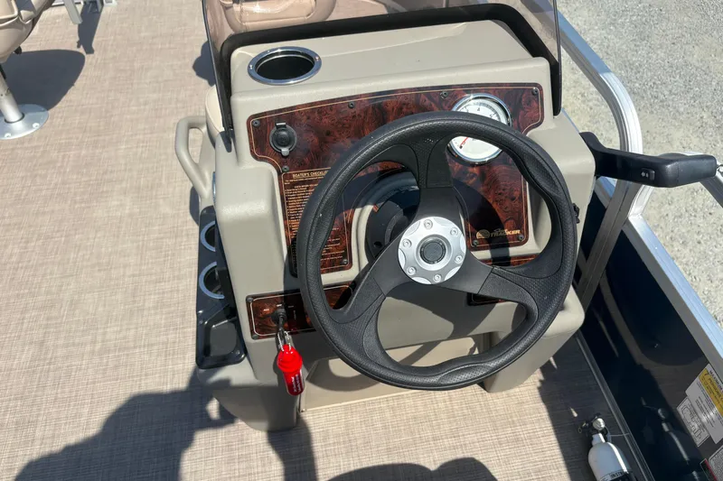 Slide: The Image of 2024 Sun Tracker Bass Buggy 16 DLX steering console with black wheel and control panel. - 7
