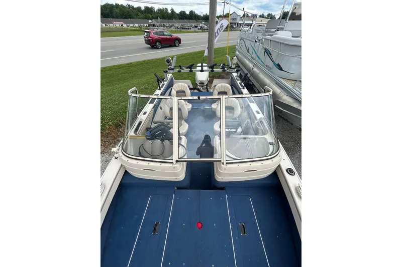 Slide: The Image of 2001 Crestliner 1850 O/B boat with blue interior, parked near a road and other boats. - 7