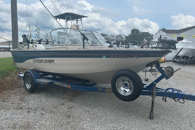 Slide: The Image of 2001 Crestliner 1850 O/B boat on trailer, parked outdoors under cloudy sky. - 1