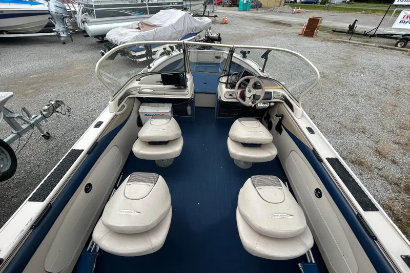 Slide: The Image of 2001 Crestliner 1850 O/B boat interior with seating and steering wheel, parked on gravel. - 10