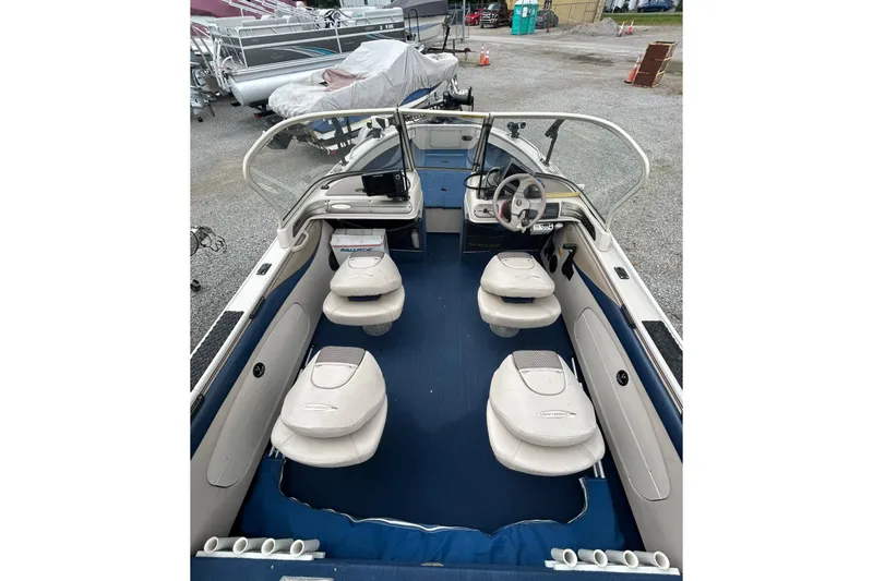 Slide: The Image of 2001 Crestliner 1850 O/B boat interior with seating and steering wheel, parked outdoors. - 4