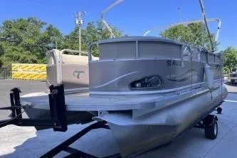 Slide: The Image of 2012 Avalon Tahoe pontoon boat on trailer, parked outdoors with trees in background. - 5