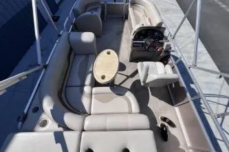 Slide: The Image of 2012 Avalon Tahoe boat interior with beige seating and steering console. - 14