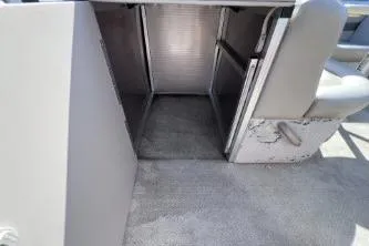 Slide: The Image of 2012 Avalon Tahoe boat interior storage compartment with open hatch and seating. - 16