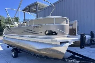 Slide: The Image of 2012 Avalon Tahoe pontoon boat on trailer, parked near a building. - 3