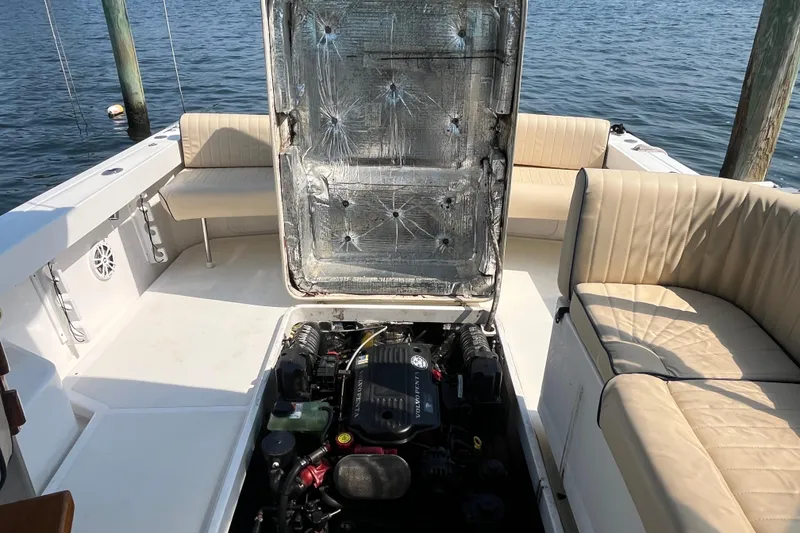 Slide: The Image of 2004 Hunt Yachts Surfhunter 29 with open engine compartment, beige seating, and ocean backdrop. - 26