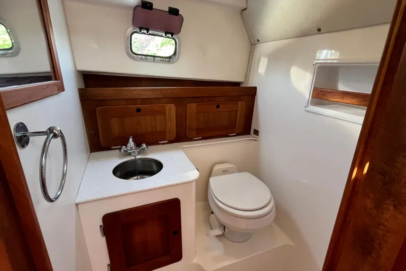 Slide: The Image of 2004 Hunt Yachts Surfhunter 29 bathroom with sink, toilet, and wooden cabinetry. - 23