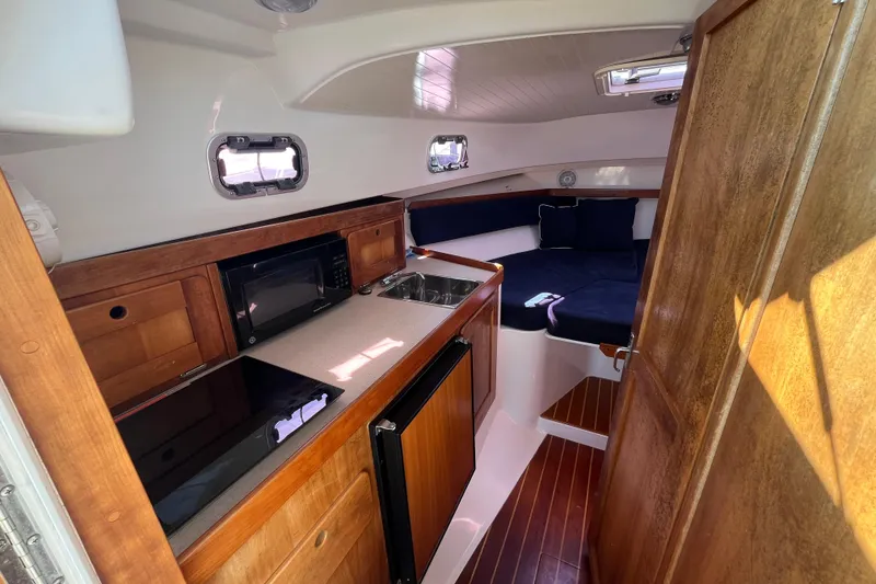 Slide: The Image of Interior of 2004 Hunt Yachts Surfhunter 29, featuring a compact kitchen and cozy seating area. - 19