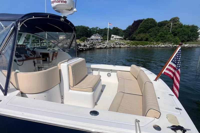 Slide: The Image of 2004 Hunt Yachts Surfhunter 29 with American flag, docked near a scenic shoreline. - 5