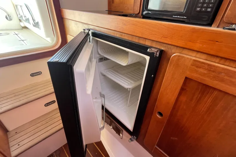 Slide: The Image of Open refrigerator in 2004 Hunt Yachts Surfhunter 29 cabin, showcasing wooden interior design. - 22