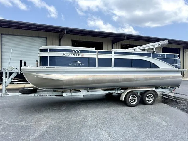 The Image of A 2023 Bennington 22 SXSAPG pontoon boat on a trailer in front of a building. - 1