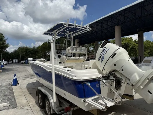 Slide: The Image of A blue and white 2015 NauticStar 231 Coastal on a trailer. It has a Suzuki outboard motor. - 12