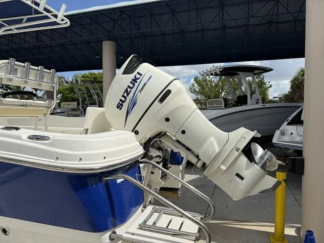 Slide: The Image of A 2015 NauticStar 231 Coastal with a Suzuki outboard motor, parked in a covered area. - 10