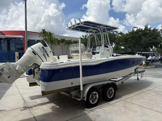 Slide: The Image of 2015 NauticStar 231 Coastal on a trailer, with Suzuki outboard motor, parked in front of a building. - 15