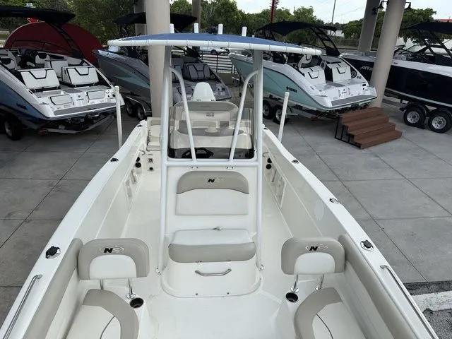 Slide: The Image of The image shows a 2015 NauticStar 231 Coastal boat in a showroom, surrounded by other boats. - 14