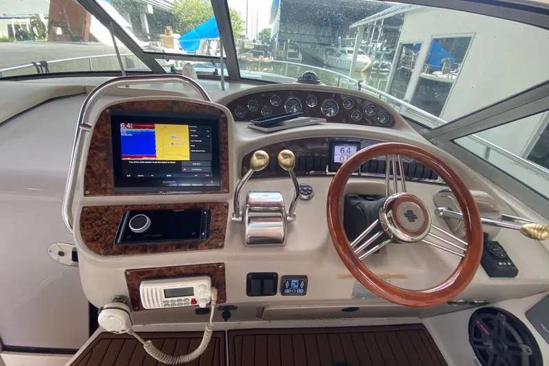 Slide: The Image of Cockpit of 2001 Sea Ray 340 Sundancer with modern navigation equipment and wooden steering wheel. - 23