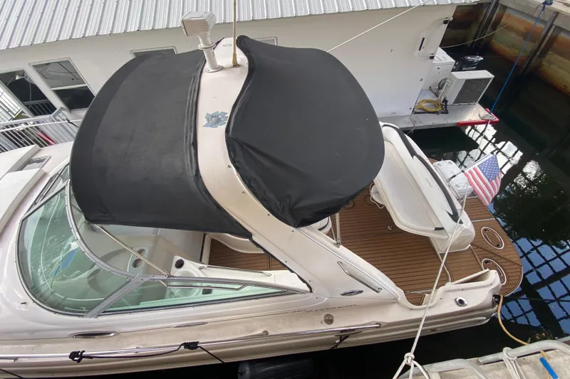 Slide: The Image of 2001 Sea Ray 340 Sundancer docked, featuring a black canopy and American flag. - 46