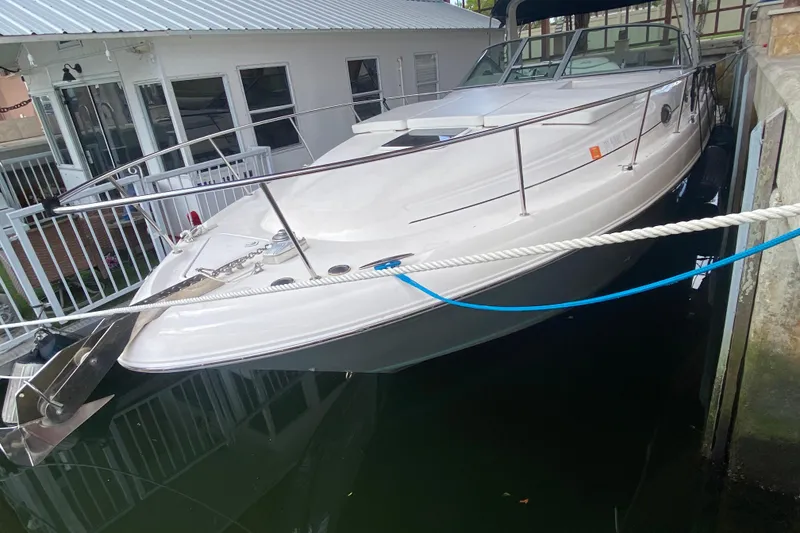 The Image of 2001 Sea Ray 340 Sundancer docked beside a house, showcasing sleek design and white exterior. - 2