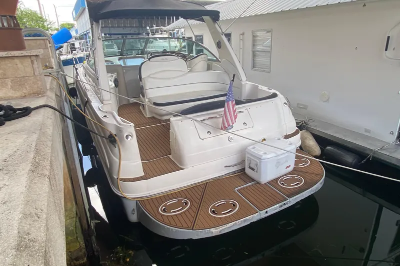 Slide: The Image of 2001 Sea Ray 340 Sundancer docked, featuring a spacious deck and American flag. - 44