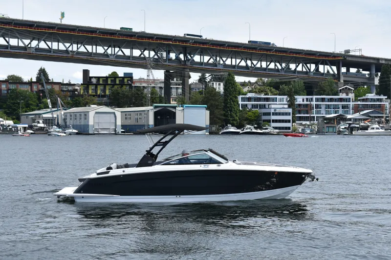 The Image of 2023 Cobalt R8 boat cruising on a river with a bridge and urban backdrop. - 0