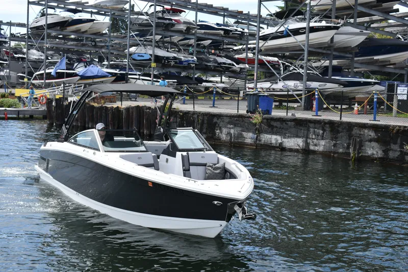 Slide: The Image of 2023 Cobalt R8 boat cruising near a marina with stacked boats in the background. - 7