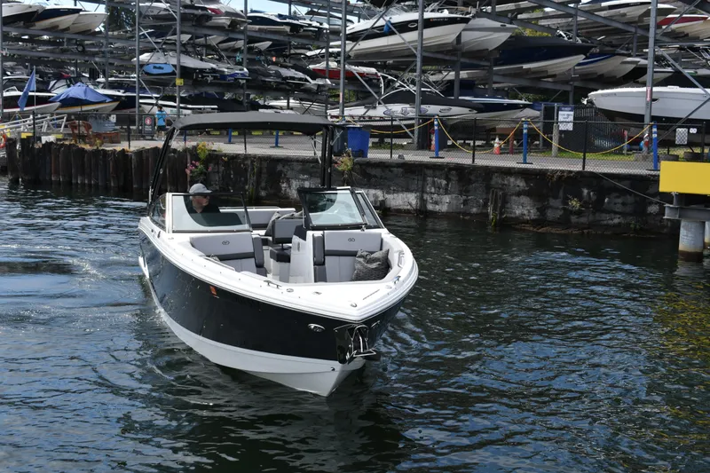 Slide: The Image of 2023 Cobalt R8 boat navigating marina waters with docked boats in background. - 9