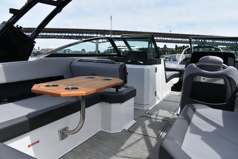 Slide: The Image of 2023 Cobalt R8 boat interior with seating and wooden table, under a bridge. - 24