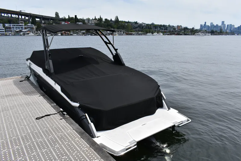 Slide: The Image of 2023 Cobalt R8 boat docked with cover, city skyline in background. - 44