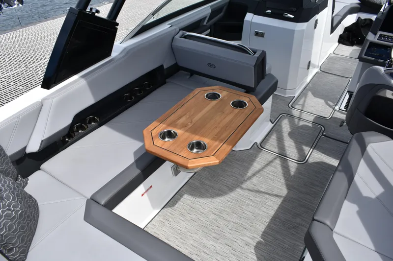 Slide: The Image of 2023 Cobalt R8 boat interior with wooden table and cup holders, featuring sleek seating. - 21