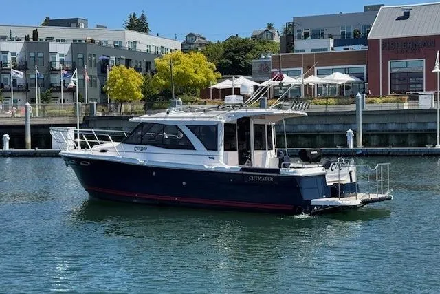 Slide: The Image of 2023 Cutwater C-30 Sedan boat docked in a marina with modern buildings in the background. - 5